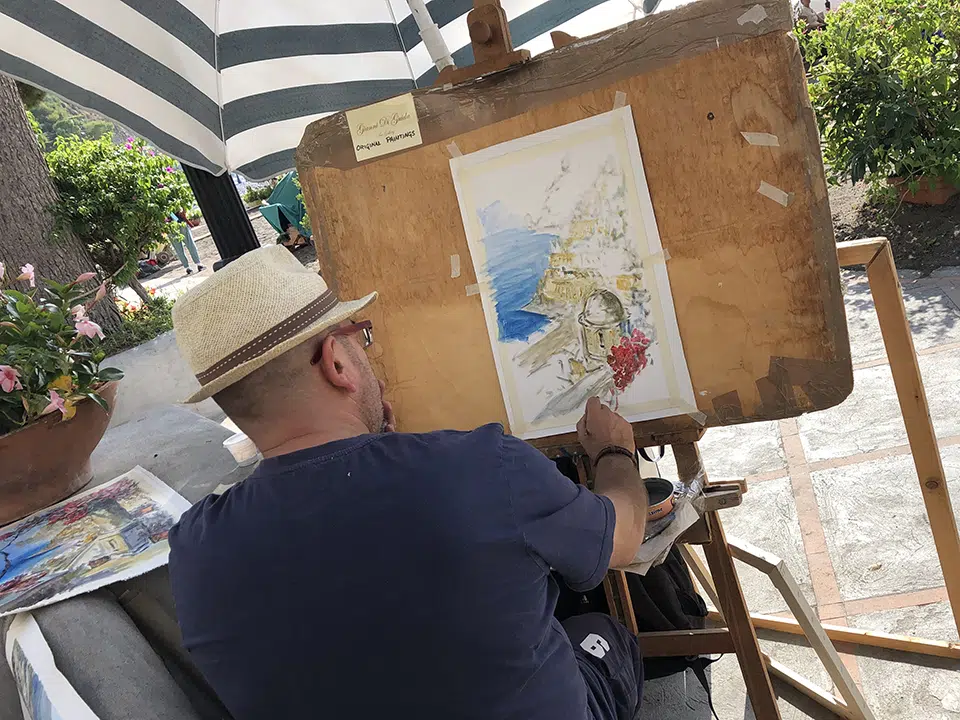 A street artist paints a view of Positano.
